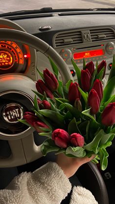 a bouquet of tulips sitting in the driver's seat of a car