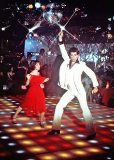 a man and woman dancing on a dance floor with disco lights in front of them