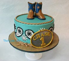 a cake decorated with cowboy boots on top of a hat and plaque that says chase 1