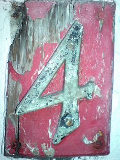 the number four is painted on an old red and white sign with rusted paint