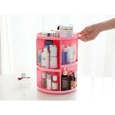 a person is holding out their hand over a pink shelf with bottles and containers on it