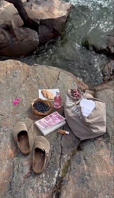 shoes and other items are sitting on the rocks by the water