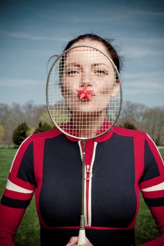 a woman holding a tennis racquet in front of her face with a red nose