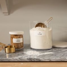 a marble counter top topped with lots of white stuff next to a jar of flour