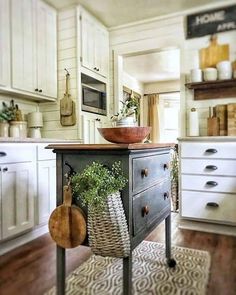 a kitchen island with a bowl on top in front of white cabinets and wooden floors