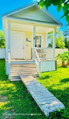 a small white house with steps leading to the front door and entryway that lead up to the porch