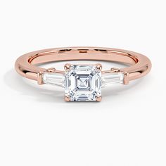 a rose gold engagement ring with an emerald and baguettes on the side, set in