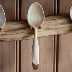 three spoons hanging from the side of a wooden rack