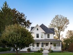 a large white house sitting on top of a lush green field