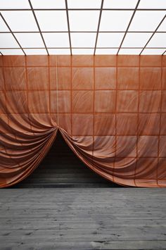 an empty room with a wooden floor and brown curtain