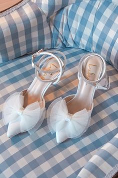 a pair of white high heeled shoes sitting on top of a blue and white checkered bed