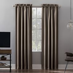 a living room with a large window covered in curtains and a television on top of a wooden table