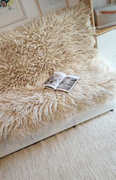 a book is laying on top of a shaggy rug in front of a wall with pictures