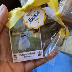 a person holding up a small card with a yellow ribbon around it's neck