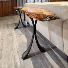 a wooden table sitting on top of a living room floor next to a white couch