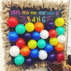 a bunch of balloons that are in front of a bulletin board with the words let's end the year with bang on it