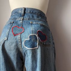 A mannequin wearing a pair of jeans with heart patches. Heart Pocket Pants, Unique Jeans Diy, Patchwork Baggy Jeans, Jean With Patches, Heart Embroidered Jeans, Jean Patches Ideas, Patch On Jeans, Hand Embroidery Jeans, Patchwork Jeans Diy