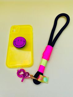 a cell phone and lanyard with a smiley face on the case next to each other