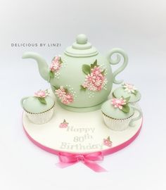 a birthday cake with cupcakes and teapot on it