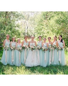 a group of women standing next to each other on top of a lush green field