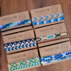 six different bracelets sitting on top of a wooden table next to a package of matches