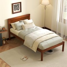 a bed with white sheets and pillows in a room next to a lamp on the floor