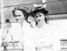 two women standing next to each other in front of a tennis court net with their hands on their hips