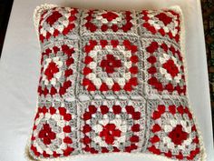 a red and white crocheted pillow sitting on top of a table