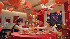 a group of people sitting around a table with food and confetti in front of them