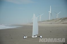 a sailboat on the beach with wind turbines in the background