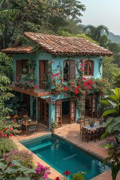 an outdoor swimming pool surrounded by greenery and flowers with a house in the background