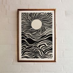 a black and white art piece hanging on the wall next to a brick wall with a round hole in it