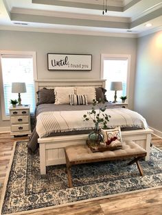 a bed room with a neatly made bed and a large rug on the wooden floor