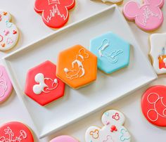 mickey mouse cookies on a plate with other decorated cookies in the shape of hexagons