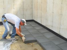 a man is laying concrete on top of the floor in front of a cement wall