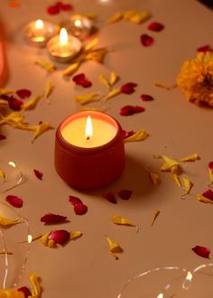 two candles sitting on top of a table covered in rose petals and petals scattered around