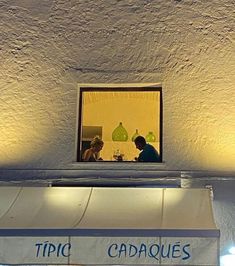 two people sitting at a table in front of a window with the words tripic cadaoes on it