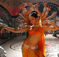 a belly dancer in an orange outfit with her arms spread out and hands extended up