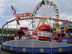 an amusement park ride that is blue, red and white with a ferris wheel in the background