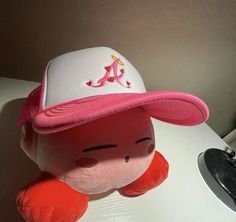 a pink and white stuffed animal wearing a baseball cap