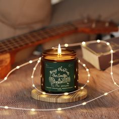 a candle sitting on top of a wooden table next to a string of lights and a guitar