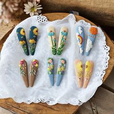 seven painted wooden flowers are arranged on a doily