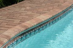 an empty swimming pool with blue water and brick edgings on the edge,