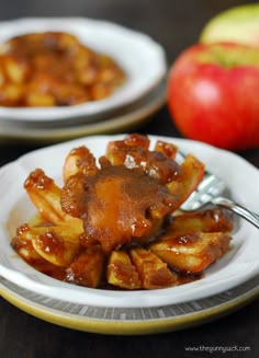 two white plates topped with food next to an apple