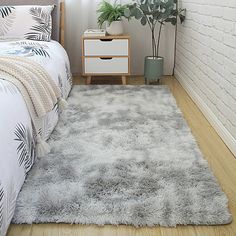 a bedroom with a bed, nightstand and plant on the side table in front of it