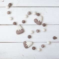 some white and gray decorations on a wooden table with balls around the edges, including two heart shaped ornaments