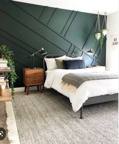 a bedroom with dark green walls, white bedding and gray carpeted flooring