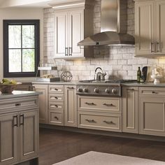 a stove top oven sitting inside of a kitchen next to white cupboards and drawers