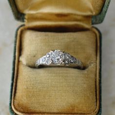 three stone diamond ring in an old - fashioned box on the floor with its lid open