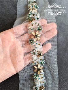 a person holding onto a piece of fabric with beads and stones attached to the end